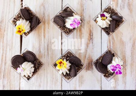 Schwarz-weiße Schokolade mit Plätzchen triflen. Dekoriert mit einer Blume auf altem weißen Holzhintergrund. Traditionelles süßes Dessert in englischer Sprache. Stockfoto