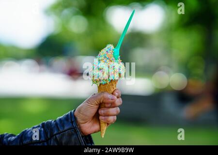 Mann mit Eiskegel. Detail von Eis mit Regenbogen bestreut in der Hand Stockfoto