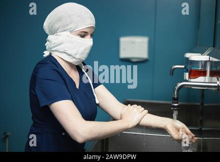 Der Chirurgenarzt in der medizinischen Maske desinfiziert die Hände vor der Operation. Stockfoto