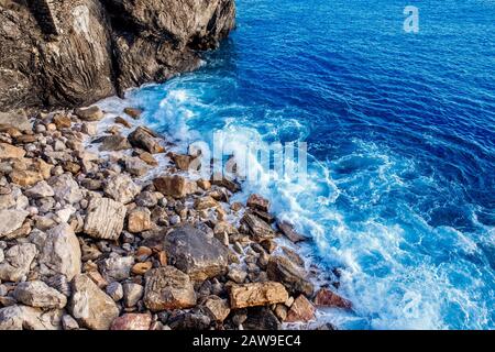 Draufsicht auf blaues Ozeanwasser, Wellen brechen auf Steinen. Konzeptfreiheit, Stärke. Stockfoto