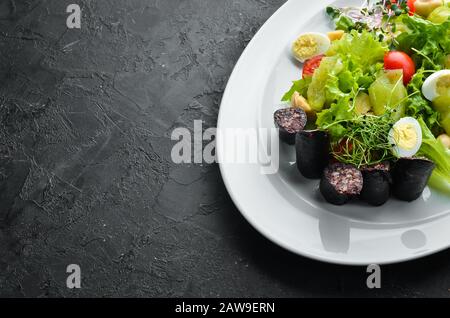 Salat mit Gemüse, Blutwurst und Pilzen auf einem Teller. Draufsicht. Freier Speicherplatz für Ihren Text. Rustikaler Stil. Stockfoto