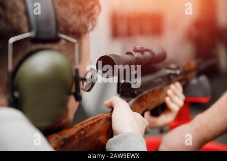 Schusswaffenpistole. Mann schießt in Kopfhörer mit Lärmschutz auf Pistole. Stockfoto