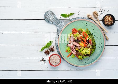 Gemüsesalat mit Avocado und Kalbfleisch. In der Platte. Draufsicht. Freier Speicherplatz für Ihren Text. Rustikaler Stil. Stockfoto