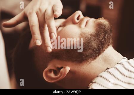Gesichtslotion nach der Rasur im Barber Shop. Die Hände schließen sich Stockfoto
