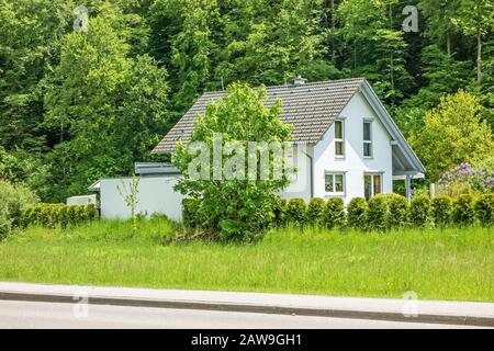 Haus / Haus mit Hof, Bäumen und Sträuchern herum - Bäume / Wald im Hintergrund Steinheim am Albuch, Deutschland - 26. Mai 2016: Wohnheim mit Stockfoto