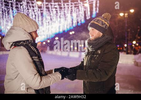 Liebevolles Paar, das sich auf der Eislaufbahn umarmt. Konzept der Weihnachtsfeiertage. Stockfoto