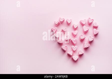 Rosafarbene, herzförmige Marshmallows, die auf einem rosafarbenen Hintergrund gestapelt sind und Platz für Kopien bieten. Marshmallow Heart.Valentine's Day Konzept Thema im Vintage-Stil. Stockfoto