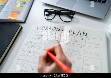 Nahaufnahme einer menschlichen Hand Workout Plan auf Notebook Stockfoto
