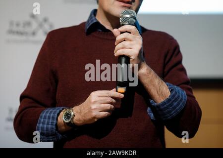 Flache Schärfentiefe (selektiver Fokus) mit den Händen eines Mannes, der ein Mikrofon hält und eine Sprache liefert. Stockfoto