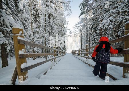 Januar 2020 - Malye Korely. Kleinkind auf einer Holztreppe in einem verschneiten Wald. Russland, Region Archangelsk Stockfoto