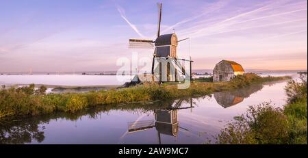 Atemberaubendes Panoramabild einer Windmühle und Nebelbänke in der Nähe von Leiden in Den Niederlanden Stockfoto