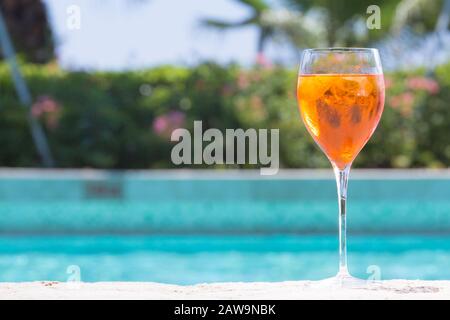 Ein Glas Aperol Spritz-Cocktail am Pool, der im tropischen Resort nass wird. Horizontal, Cocktail auf der rechten Seite Stockfoto