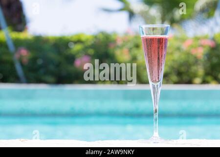Ein Glas Kir Royal Cocktail am Pool im tropischen Resort. Horizontal, Cocktail auf der rechten Seite Stockfoto