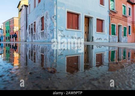 Die farbenfrohen Häuser von Burano spiegelten sich in einer Pfütze, Burano, Venedig, Italien, wider Stockfoto