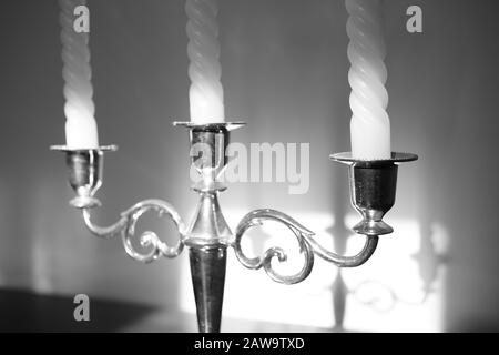 Kerzenleuchter mit drei Kerzen. Schattenreflexion an der Wand. Schwarzweißfoto Stockfoto