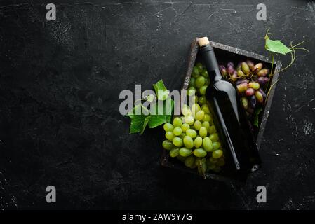 Rotwein und frische Trauben auf schwarzem Steintisch. Draufsicht. Freier Speicherplatz für Ihren Text. Stockfoto