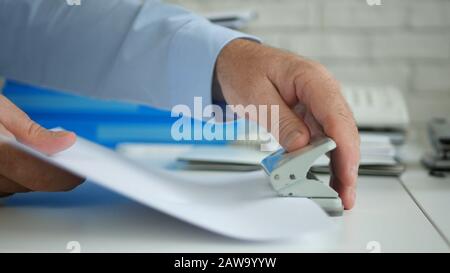 Vielbeschäftigte Geschäftsleute in Office Archivieren Dokumente und Verträge mit einem Papierperforator Stockfoto