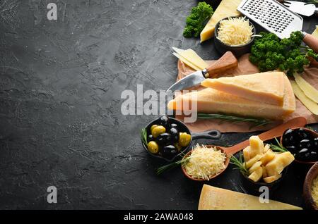 Satz harter Käse mit Käsemessern auf schwarzem Steingrund. Parmesan. Draufsicht. Freier Speicherplatz für Ihren Text. Stockfoto