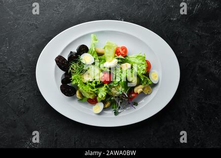 Salat mit Gemüse, Blutwurst und Pilzen auf einem Teller. Draufsicht. Freier Speicherplatz für Ihren Text. Rustikaler Stil. Stockfoto