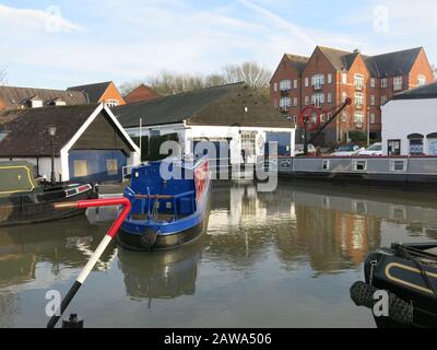 Blick auf die schmalen Boote in Braunston Marina am Canal Grande, mit einem modernen Wohnblock im Hintergrund. Stockfoto