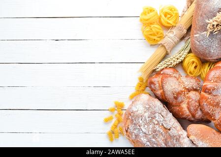 Glutenfreie Speisen. Verschiedene Pasta, Brot, Snacks und Mehl auf weißem Holzhintergrund. Draufsicht. Freier Speicherplatz für Ihren Text. Stockfoto