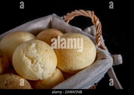 Brasilianische hausgemachte Käsepfuppe, AKA "pao de queijo" in einem rustikalen Korb. Stockfoto