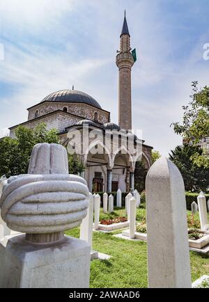 Alipasina-Moschee in Sarajevo, Bosnien und Herzegowina. Im Vordergrund steht ein turbaner Grabstein und die weißen Grabsteine im Friedhofgarten. Stockfoto