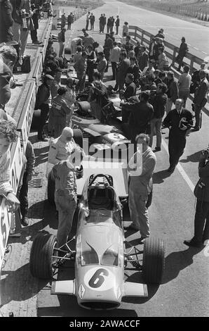 Nederlands: Nr. 6 in de Drukke pitstraat. Bruce McLaren (Mitte links, weißer Balaclava) bereitet sich vor, seinen Platz in seinem McLaren M7C Formel-1-Auto vor dem großen Preis von 1969 zu nehmen. Dahinter ist der französische Fahrer Jean-Pierre Beltoise (Helm an) kurz davor, seinen Matra MS80 zu steigen.; Stockfoto