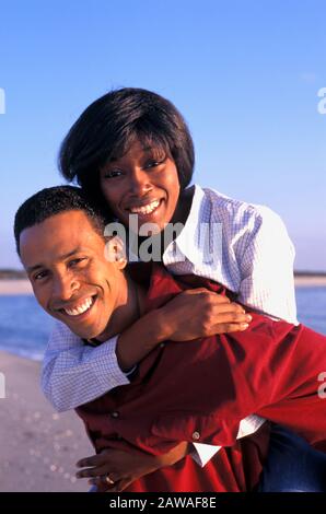 Junge afroamerikanische Paare täuschen sich herum und lieben sich auf einem Strandurlaub Stockfoto
