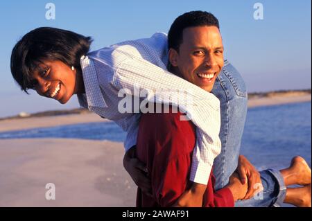 Junge afroamerikanische Paare täuschen sich herum und lieben sich auf einem Strandurlaub Stockfoto