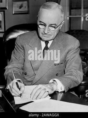 1950, USA: Präsident Harry S. Truman (* um die Zeit zwischen dem Jahr 42-1972) wird an seinem Schreibtisch im Weißen Haus gezeigt, wo er eine Proklamation unterzeichnet, die einen nationalen Notfall ausgerufen hat Stockfoto