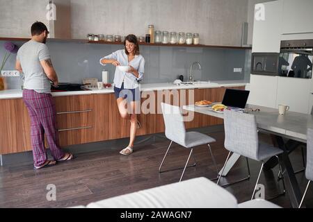 Junge Paare sprechen und genießen zusammen in der Küche, während sie Essen zubereiten. Lifestyle, modernes, lebendiges Konzept Stockfoto