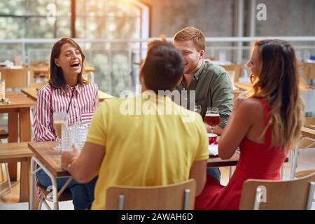 Glückliche Leute sitzen in der Kaffeemaschine haben Spaß und haben es genossen zu reden Stockfoto