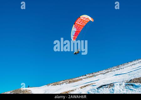 Fliegen Sie auf einem Gleitschirm über verschneiten Bergen. Stockfoto