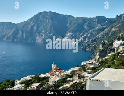 Im Vordergrund steht die gekachelte Kuppel der Kirche San Gennaro in Praiano. Gegenüber der Bucht liegt Positano an der Amalfiküste, Italien Stockfoto