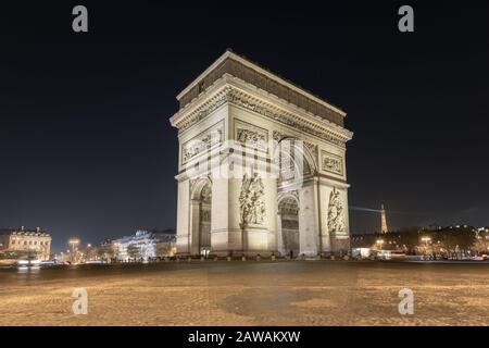 Nachtblick auf den Triumphbogen im Pariser Triumphbogen mit Tour Eiffel dahinter und wenig Verkehr. Das ist Frankreich, Das ist Paris Stockfoto