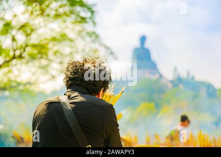 Treue Menschen von hinten, die mit Räucherstäbchen pretigen, rauchen die große Buddha-Statue in China. Stockfoto