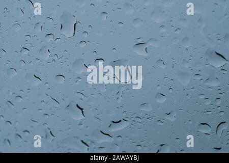 Regentropfen auf dem Fenster schließen sich. Regen fällt auf das Glasmakro. Wasser fällt auf das Fenster. Regnerischer Tag. Nasses Glas. Regentropfen durchsickern Stockfoto