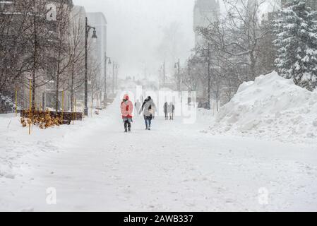 Menschen, die im Winter die Mc Tavish Street Montreal bei einem Schneesturm, schneebedeckte Straße, helle rote Jacke, Parka, untergehen Stockfoto