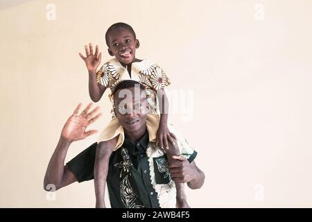Afrikanischer Vater und Kind posieren zusammen lächelnd und lachen mit Zunge vor isoliertem Hintergrund Stockfoto