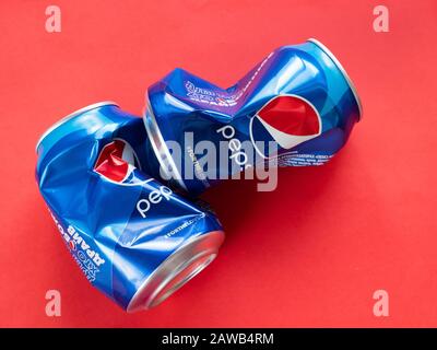 Pepsi zerknitterte Aluminiumdosen, die auf rotem Hintergrund für das Recycling vorbereitet wurden Stockfoto