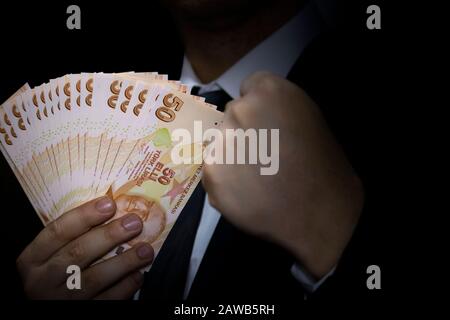 Ein erfolgreicher Geschäftsmann, der 50 türkische Lira-Banknoten in der Hand hält Stockfoto