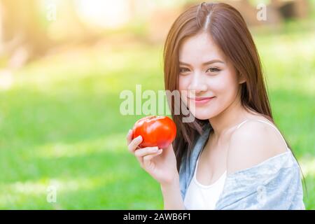 Asiatische Frauen mit Tometo für gesunde pflanzliche Nahrung hohes Beta-Carotin-Vitamin für gutes Gesundheits-Hautkonzept. Stockfoto