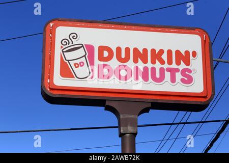 Ein Donuts von Dunkin auf einem Pfosten gegen einen sonnigen blauen Himmel Stockfoto