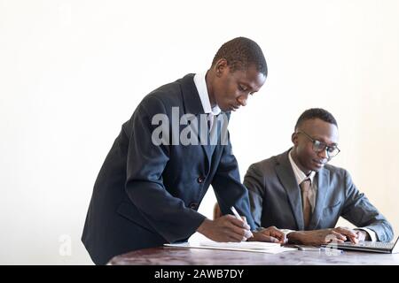 Gutaussehende schwarze Geschäftsleute arbeiten an ihrem Schreibtisch zusammen Stockfoto