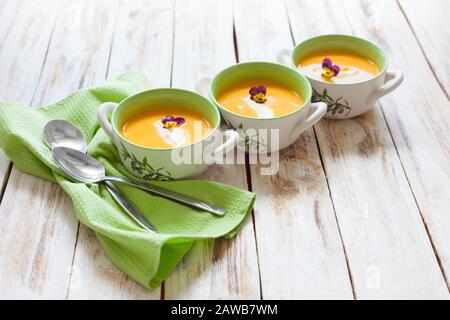 Püree Suppe aus orangefarbenem Kürbis, Süßkartoffeln und Karotten, serviert mit saurer Sahne Stockfoto