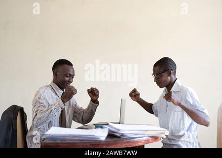 Zwei schwarze Afrikanische Mitarbeiter feiern riesige Verkäufe online im Internet Stockfoto