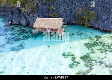 Blick von oben, atemberaubender Luftblick auf einen von felsigen Klippen umgebenen, von einem türkisfarbenen, kristallklaren Meer umgebenen, Urlaub. Stockfoto