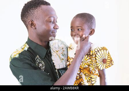 Afrikanischer Vater und Sohn posieren zusammen vor der Kamera lachen und lächeln vor weißem Hintergrund Stockfoto
