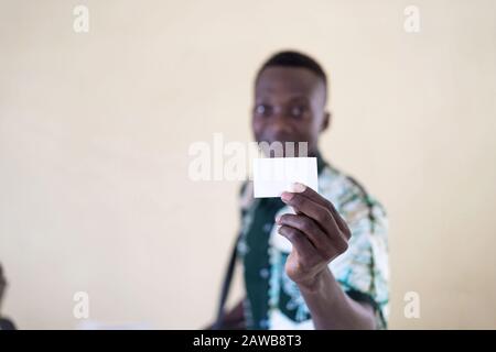 Entschärfte Aufnahme eines afrikanischen Geschäftmanns, der seine Visitenkarte in Bamako, Mali, der Öffentlichkeit zeigt Stockfoto